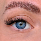 Close-up of a blue eye with detailed eyelashes and eyebrow.