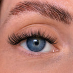 Close-up of a person's eye with long eyelashes and blue irises.